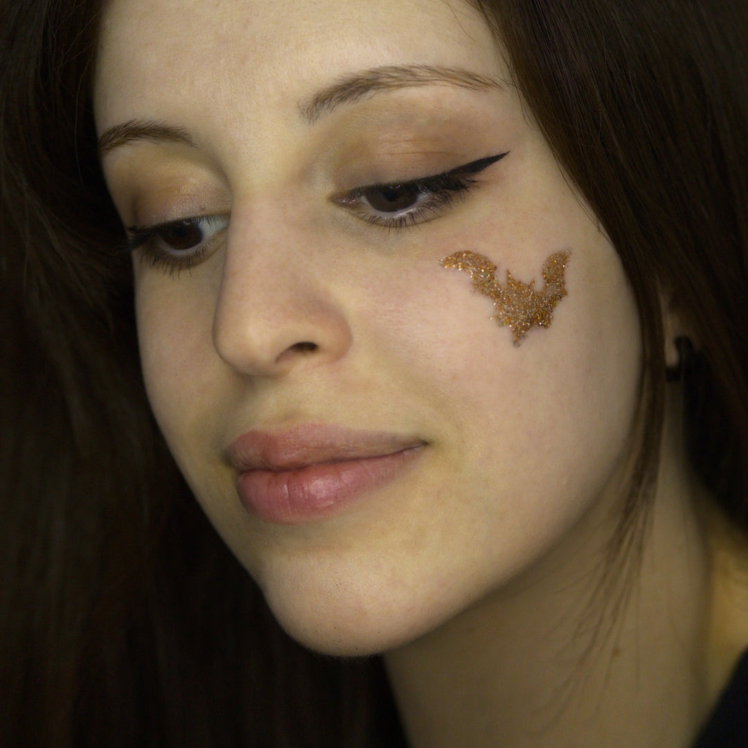 Maquillage Halloween chauve-souris avec pochoir et paillettes orange métallique